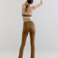 A woman wears an olive green sports bra and pants from back