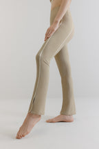 A woman wears grey flare leggings with two white lines on the sides