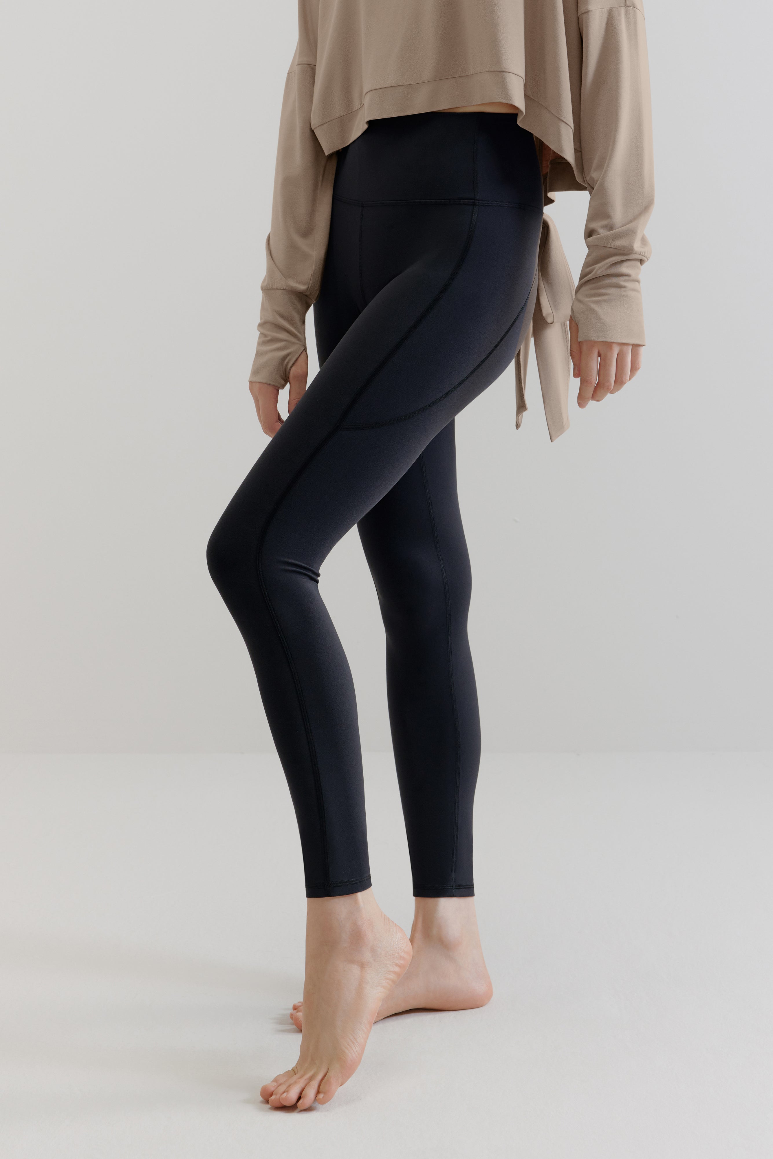 A woman wears a gray long-sleeved shirt and navy leggings.