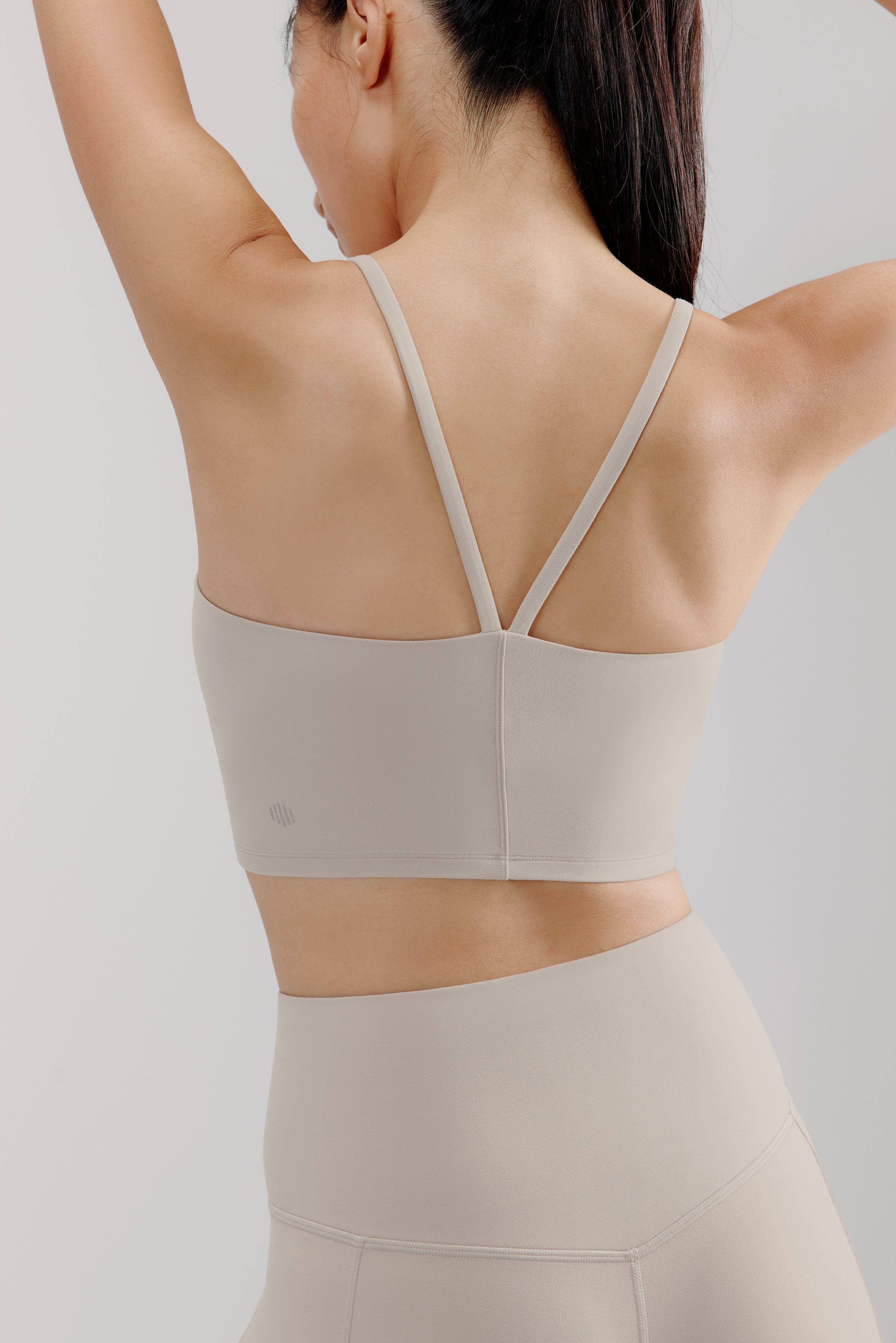 back of woman in grey sports bra and leggings