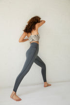 back of a woman wearing marble sports bra and dark grey leggings