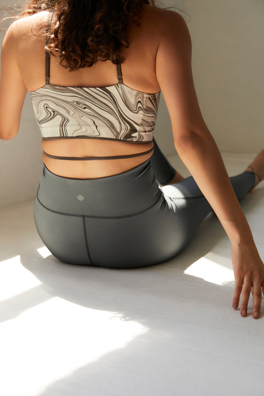 back of woman in marble sports bra and steel blue leggings