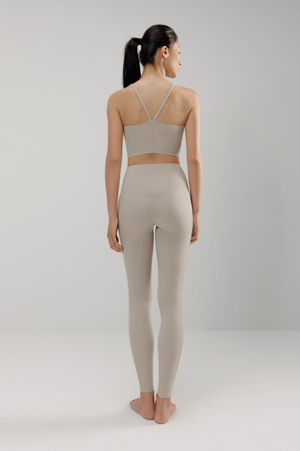 back of woman in grey sports bra and leggings