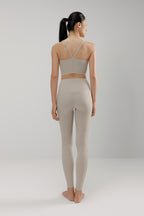 back of woman in grey sports bra and leggings