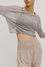 front view of a women wearing a neutral color woven jogger and a navy bra covered by a mauve color see thru knit top.