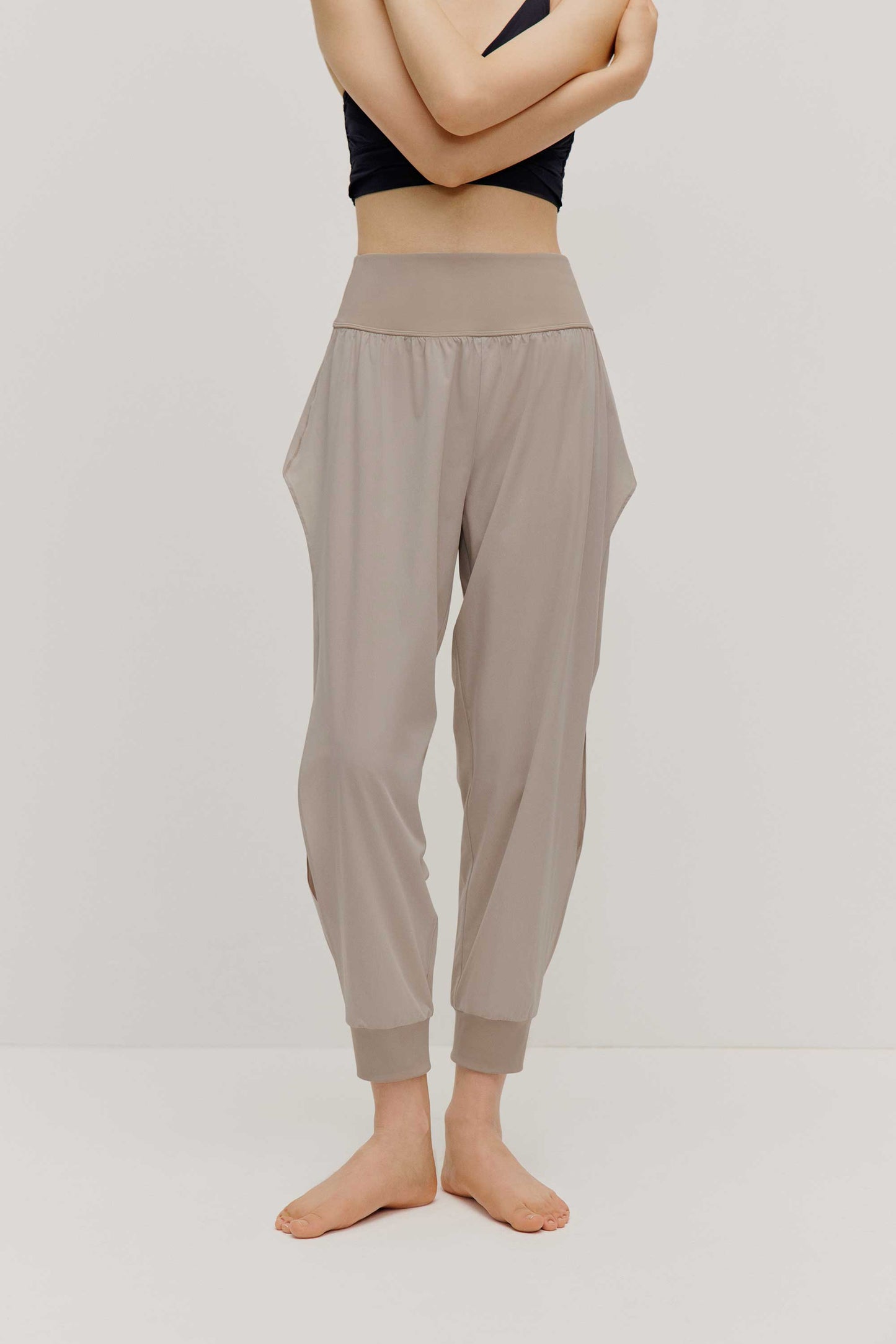 The front view of a woman wearing a pair of light grey tapered joggers with side slits