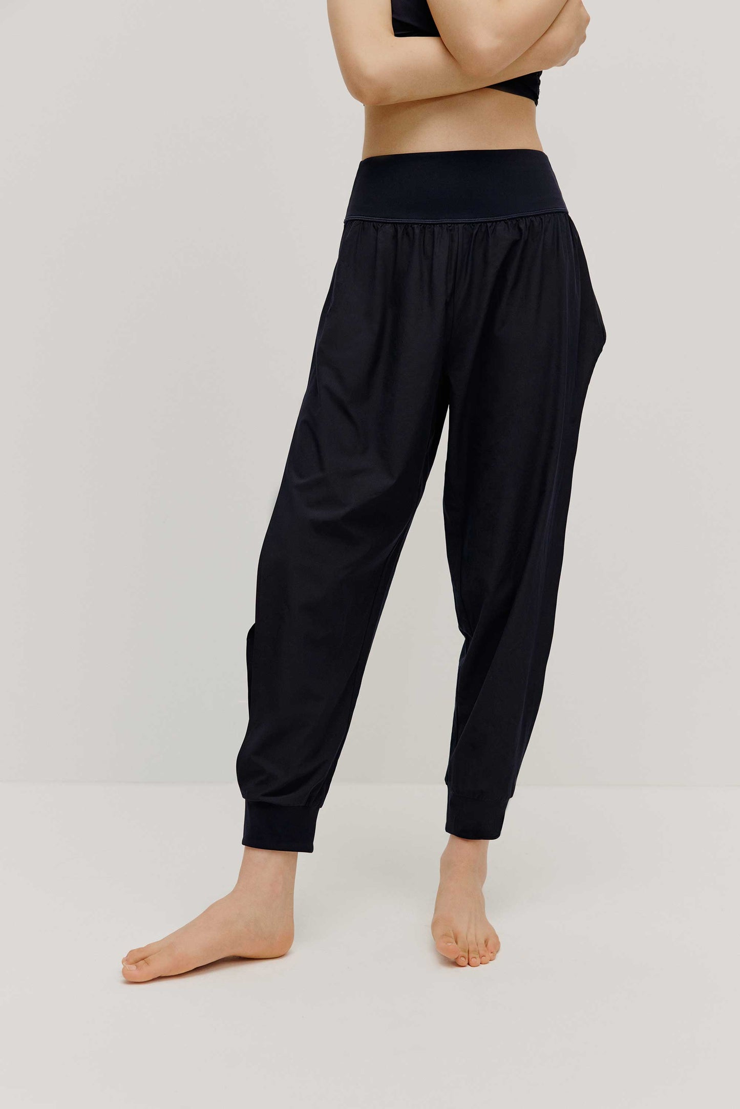 The front view of a woman wearing a pair of black tapered joggers with side slits