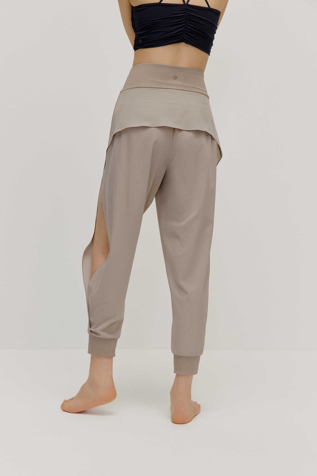 The back view of a model wearing light grey tapered joggers with NEIWAI Active logo on the waist
