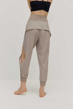 The back view of a model wearing light grey tapered joggers with NEIWAI Active logo on the waist