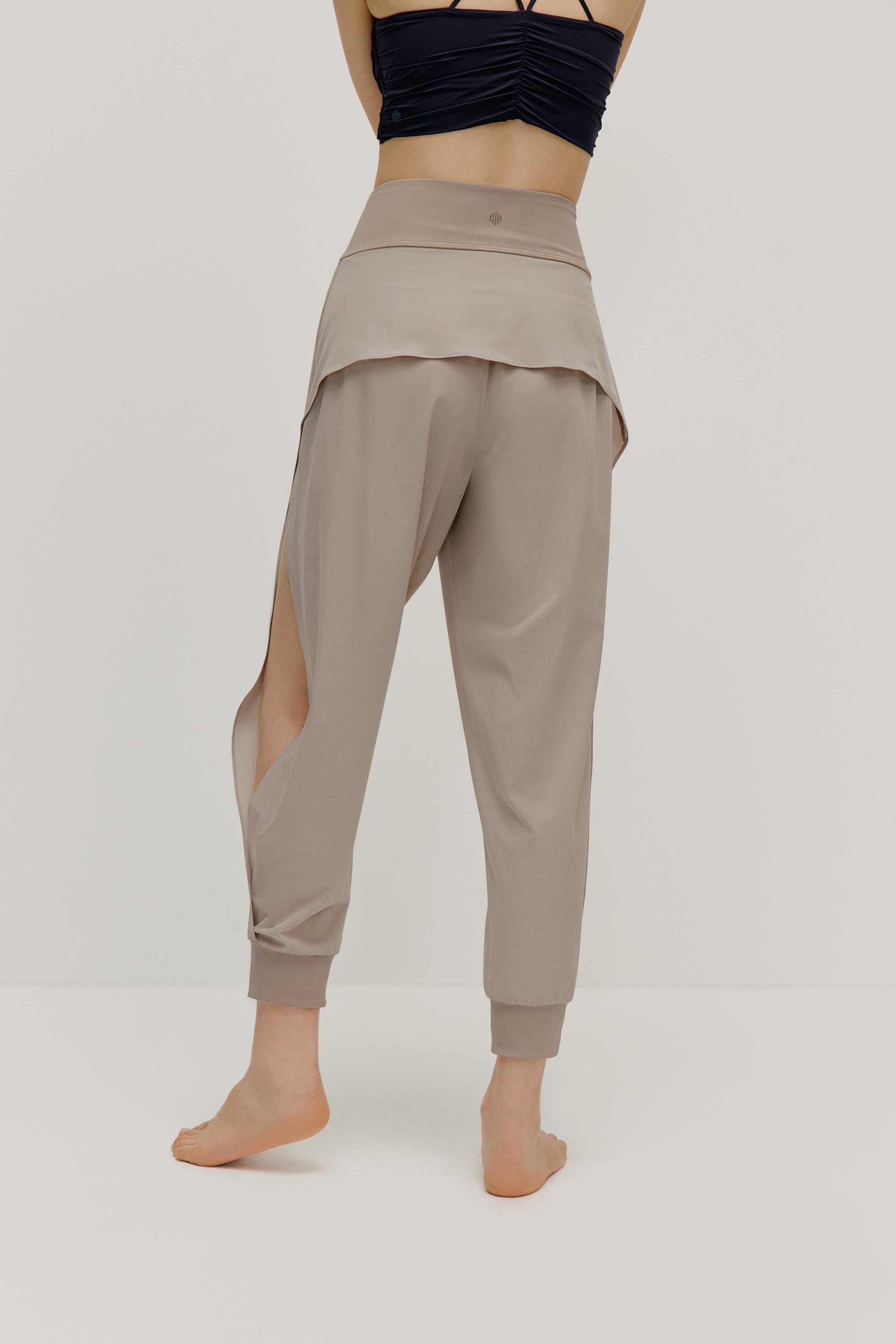 The back view of a model wearing light grey tapered joggers with NEIWAI Active logo on the waist
