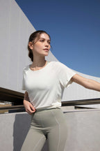 woman in white t-shirt with front knot and green sports bra and leggings