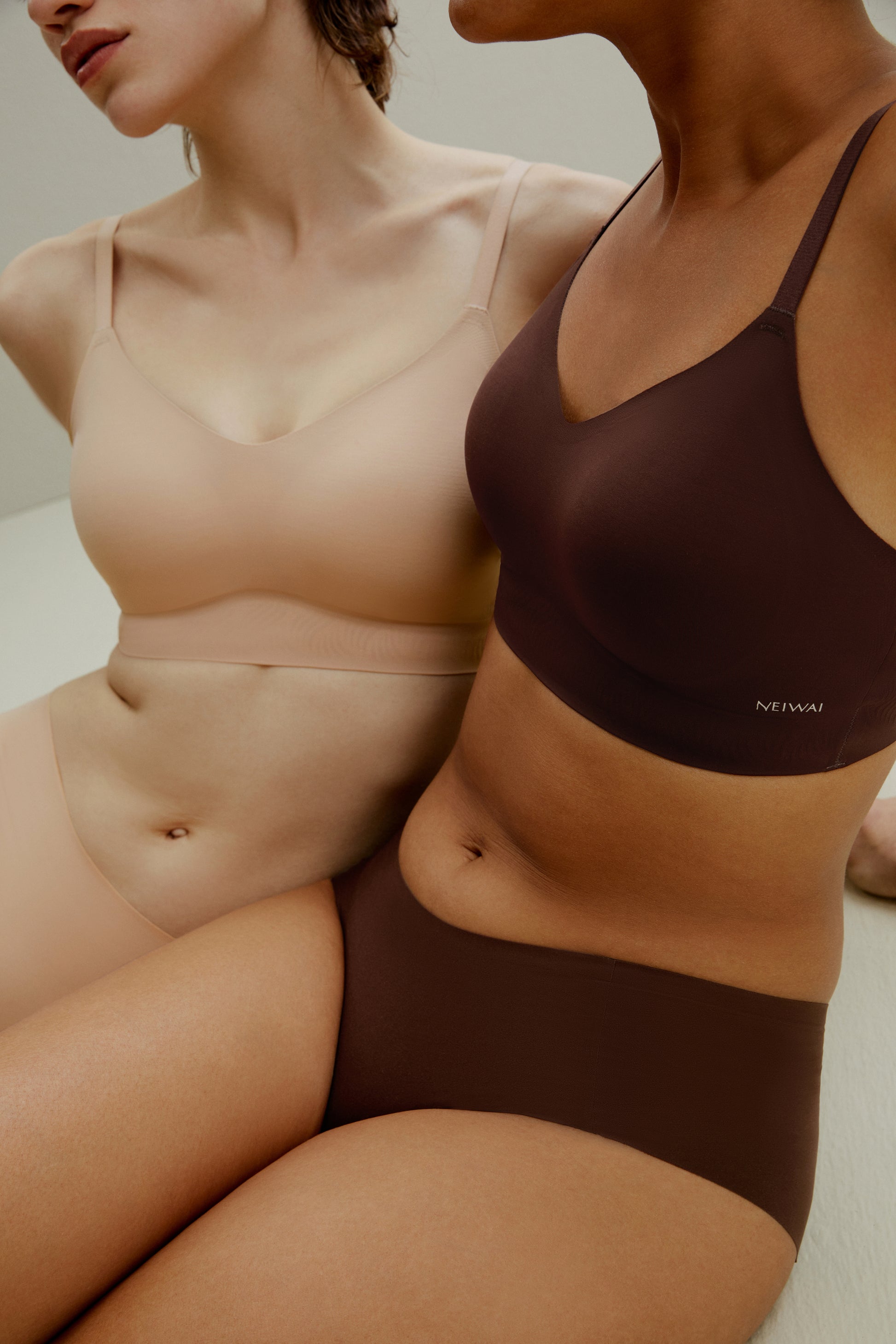 Woman wearing tan-colored bra and brief set and woman wearing brown bra and brief set