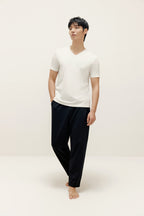 Man wearing white V-neck T-shirt and black lounge pants. White color.