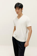 Man wearing white V-neck T-shirt and black lounge pants. White color.