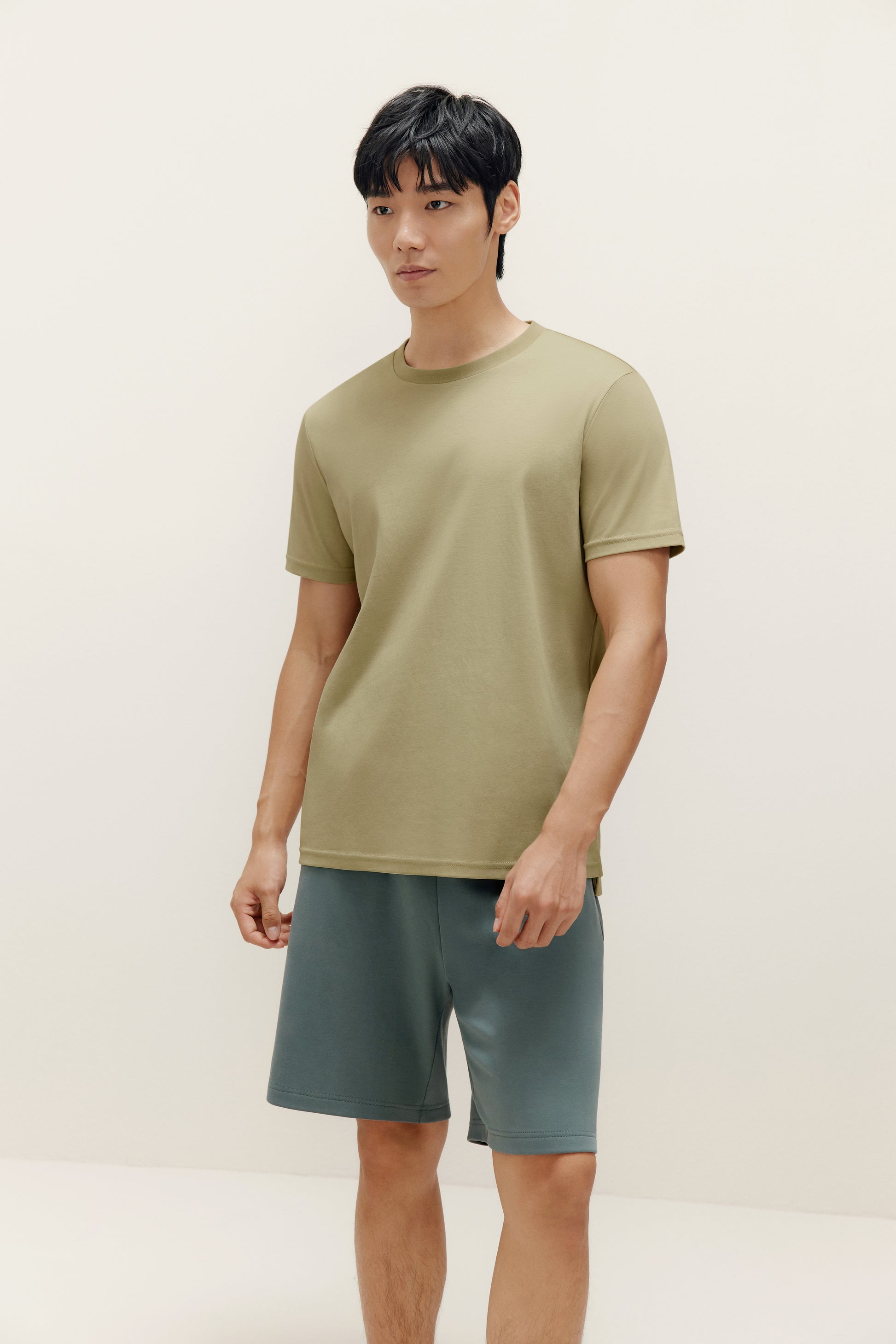 a man wearing green t shirt and dark green shorts