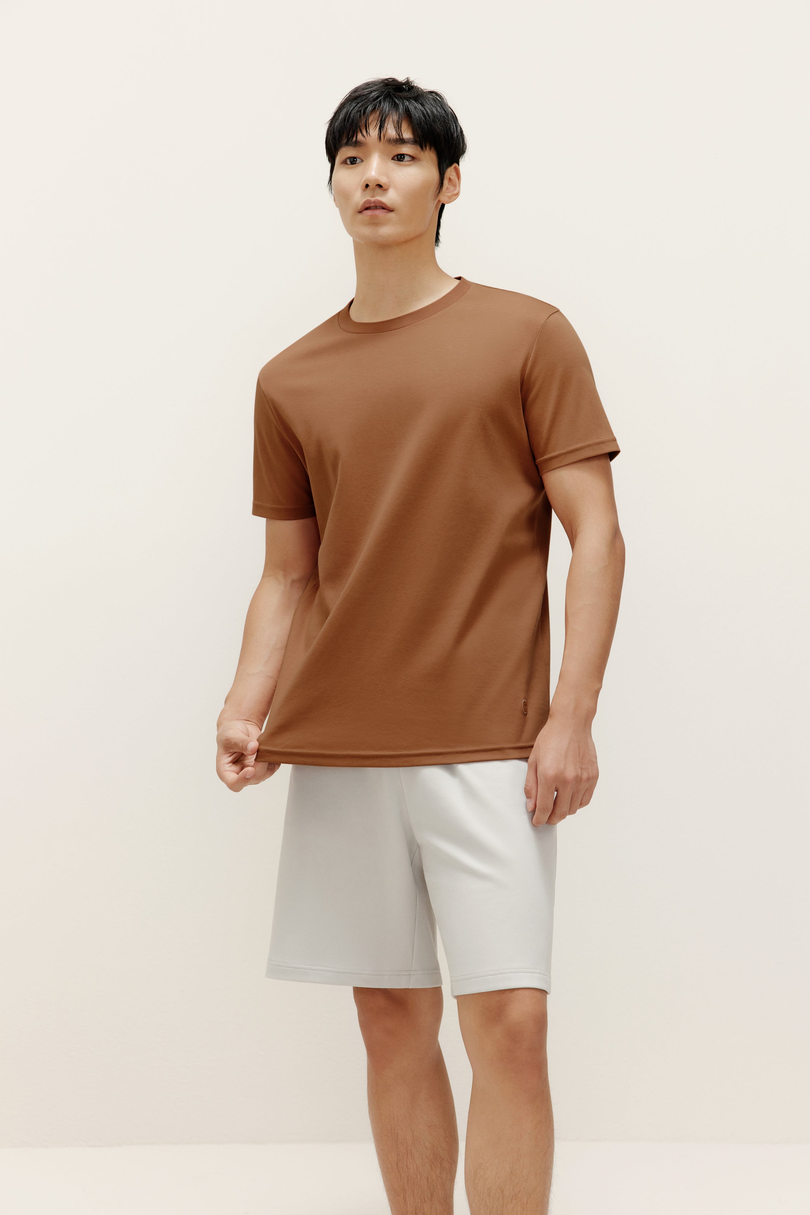 a man wearing brown t shirt and white shorts