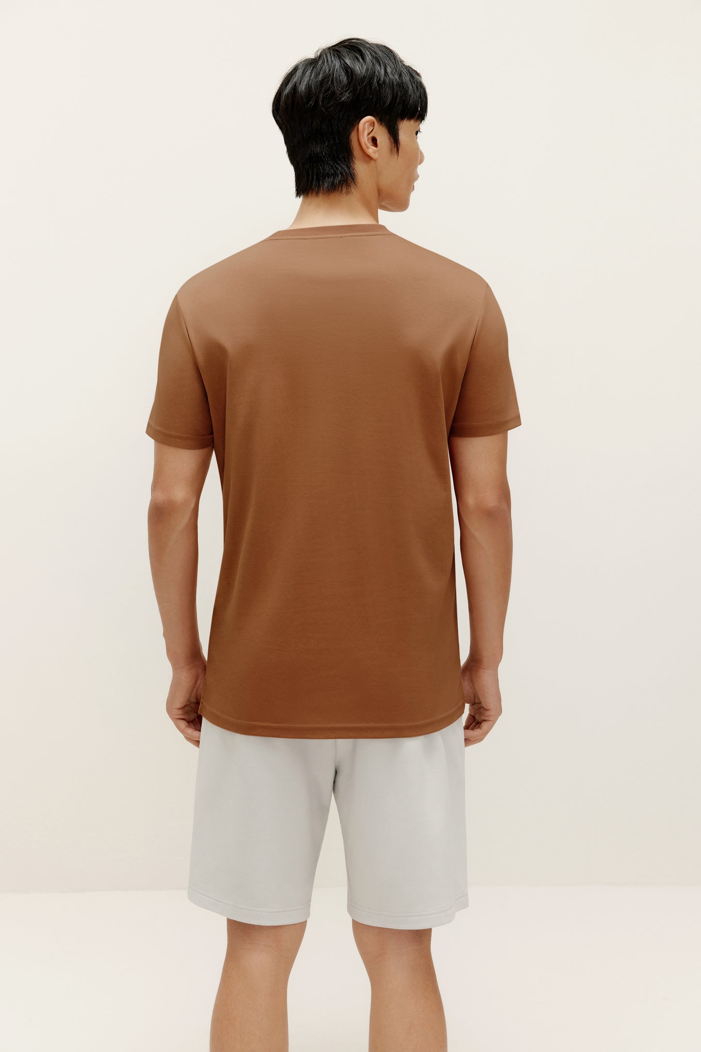back of a man wearing brown t shirt and white shorts