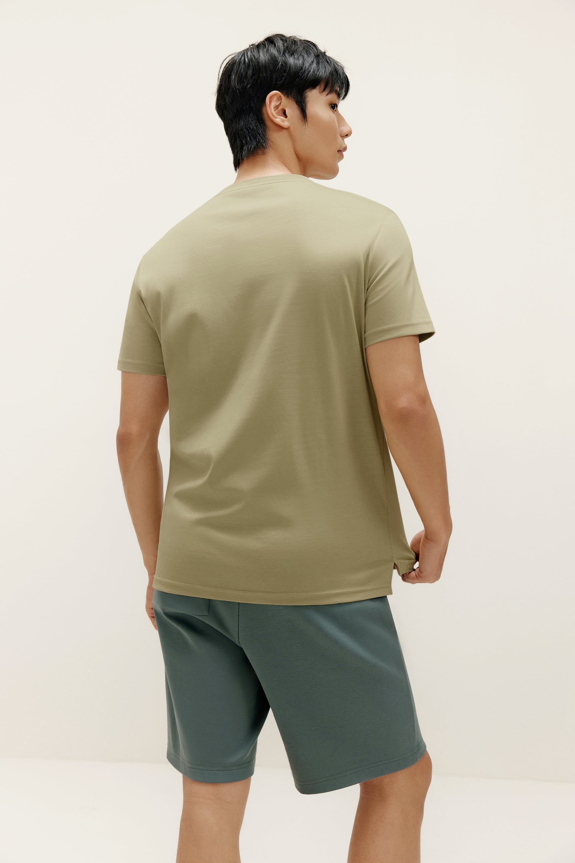 back of a man wearing green t shirt and dark green shorts