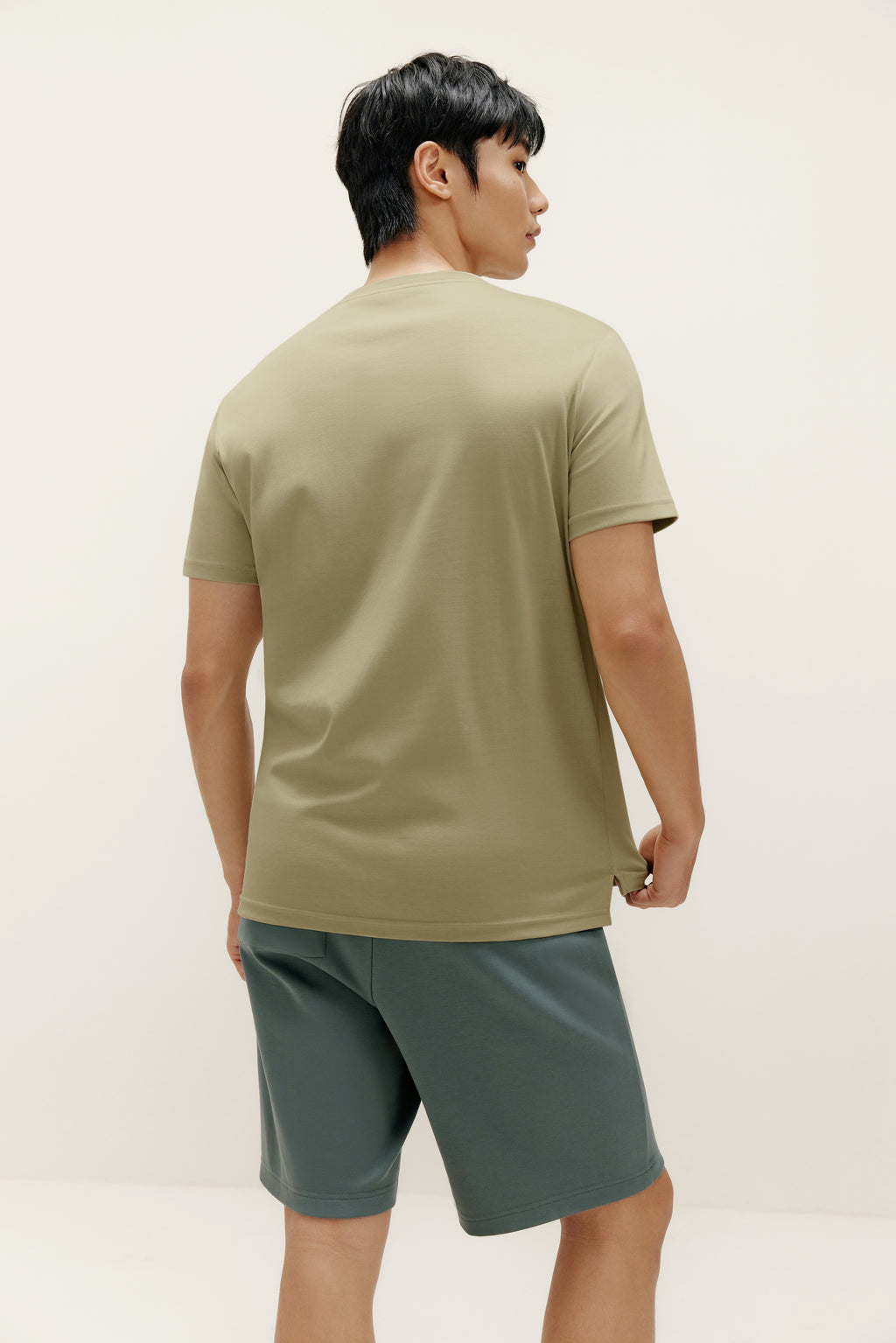 back of a man wearing green t shirt and dark green shorts