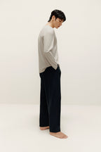 side of man wearing a grey long sleeve and black pants