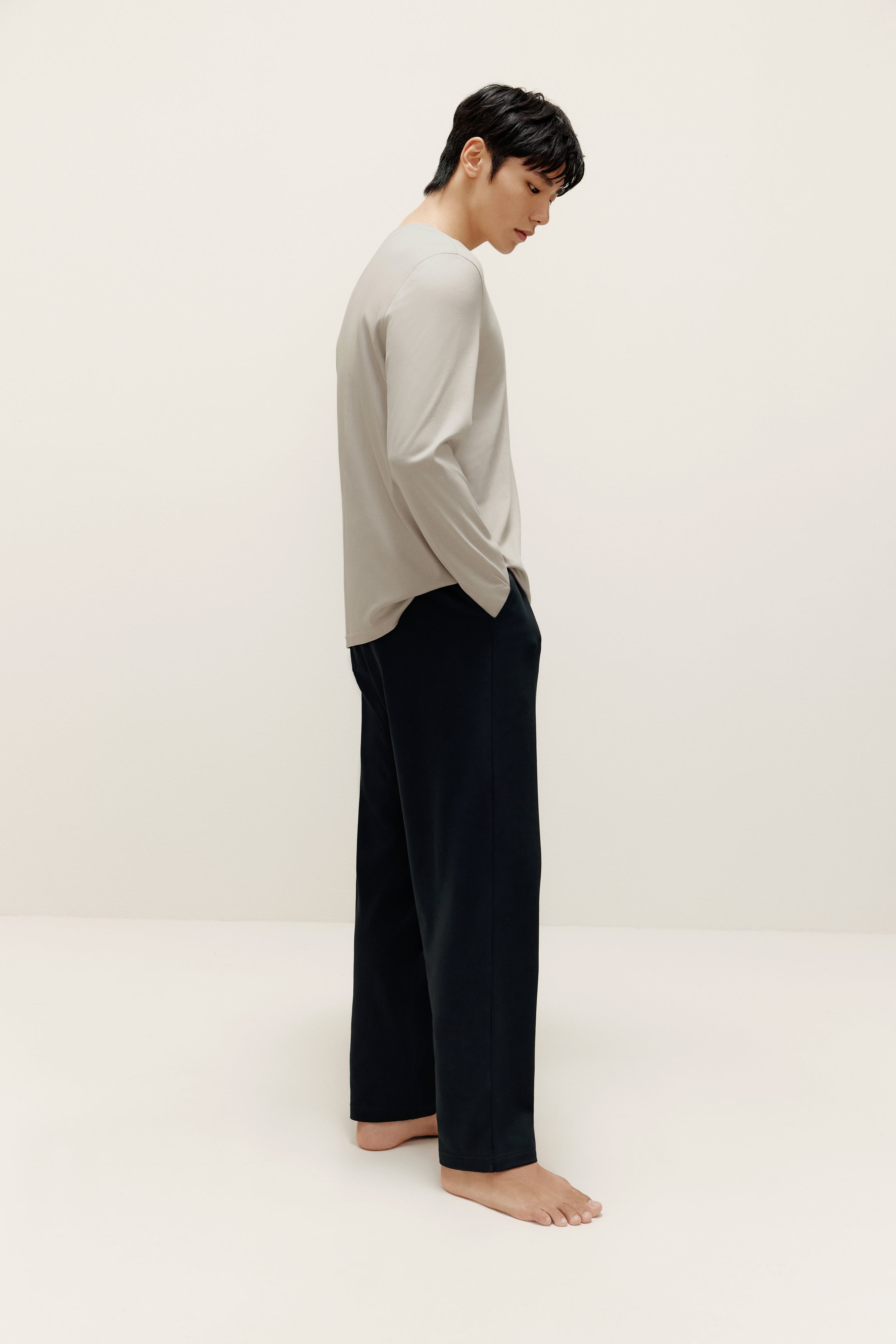 side of man wearing a grey long sleeve and black pants