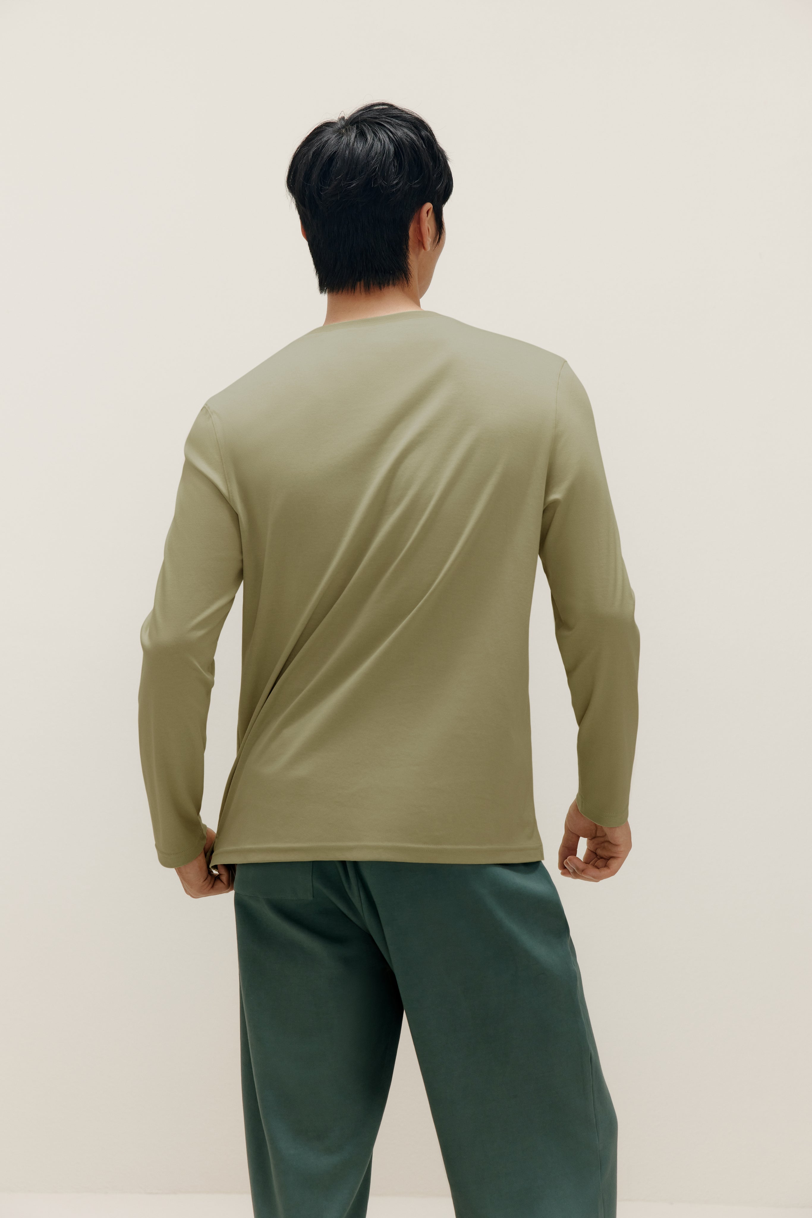 back of man wearing a green long sleeve and dark green pants