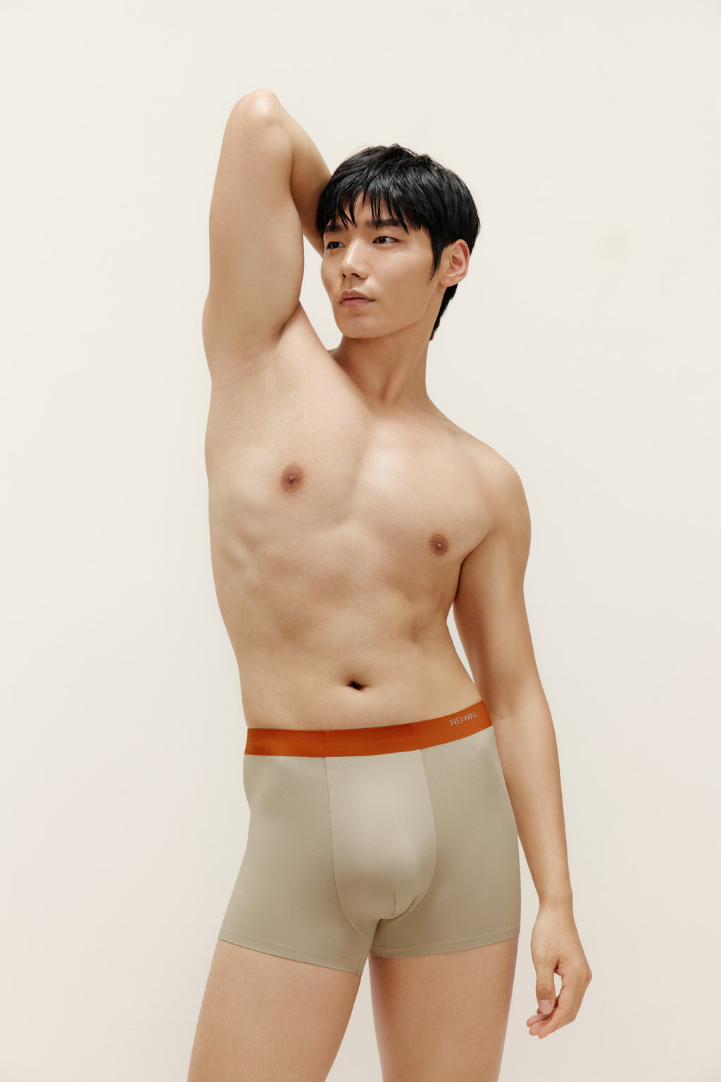 Man wearing beige boxer briefs with orange waistband. Oatmeal color. 
