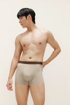 Man wearing tan boxer briefs with brown waistband. Light Heather color. 