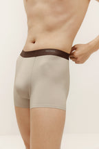 Closeup of man wearing tan boxer briefs with brown waistband. Light Heather color. 