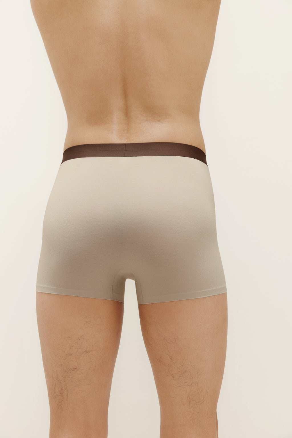 Back of man wearing tan boxer briefs with brown waistband. Light Heather color. 