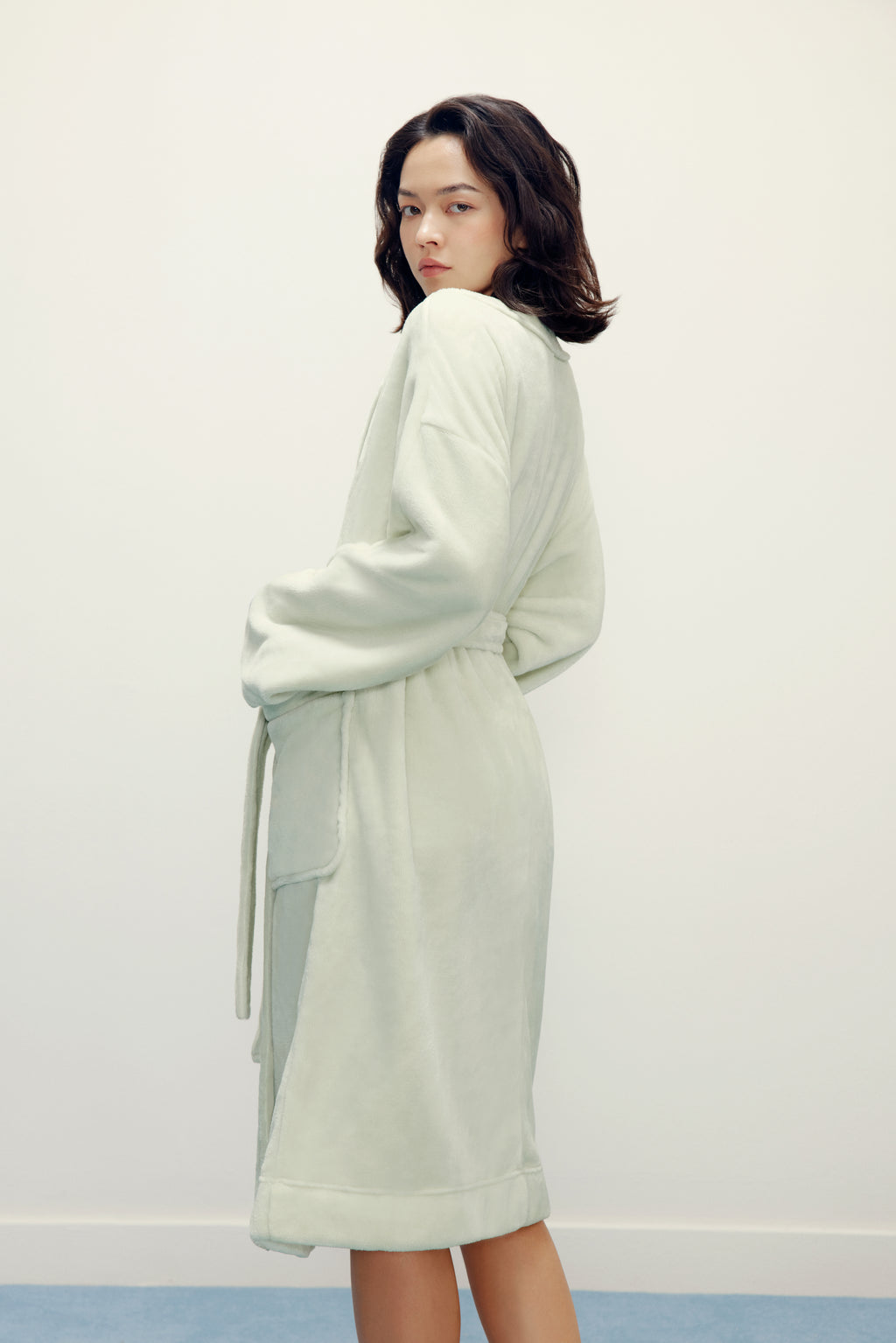 side view of woman wearing a light green fleece robe