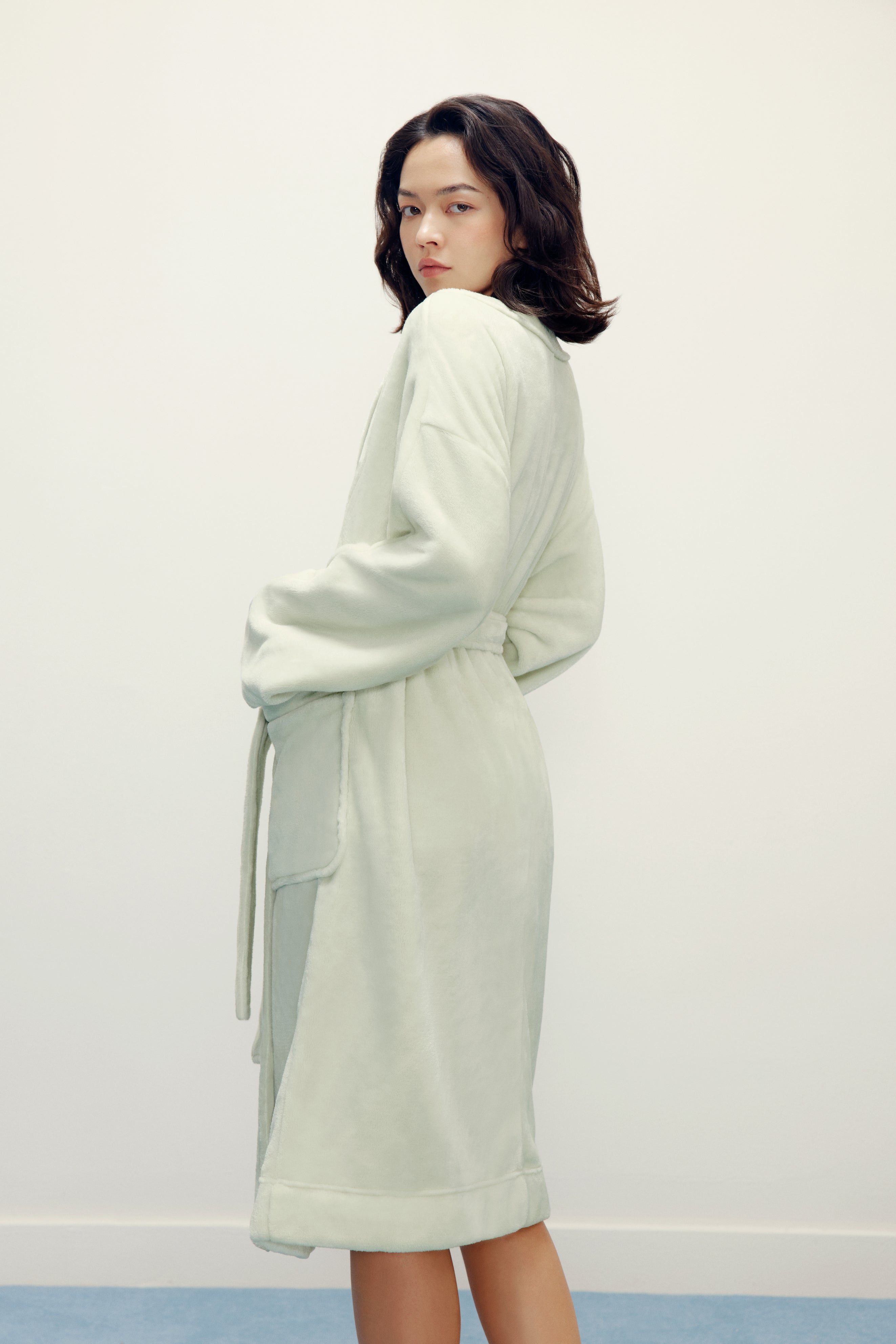 side view of woman wearing a light green fleece robe
