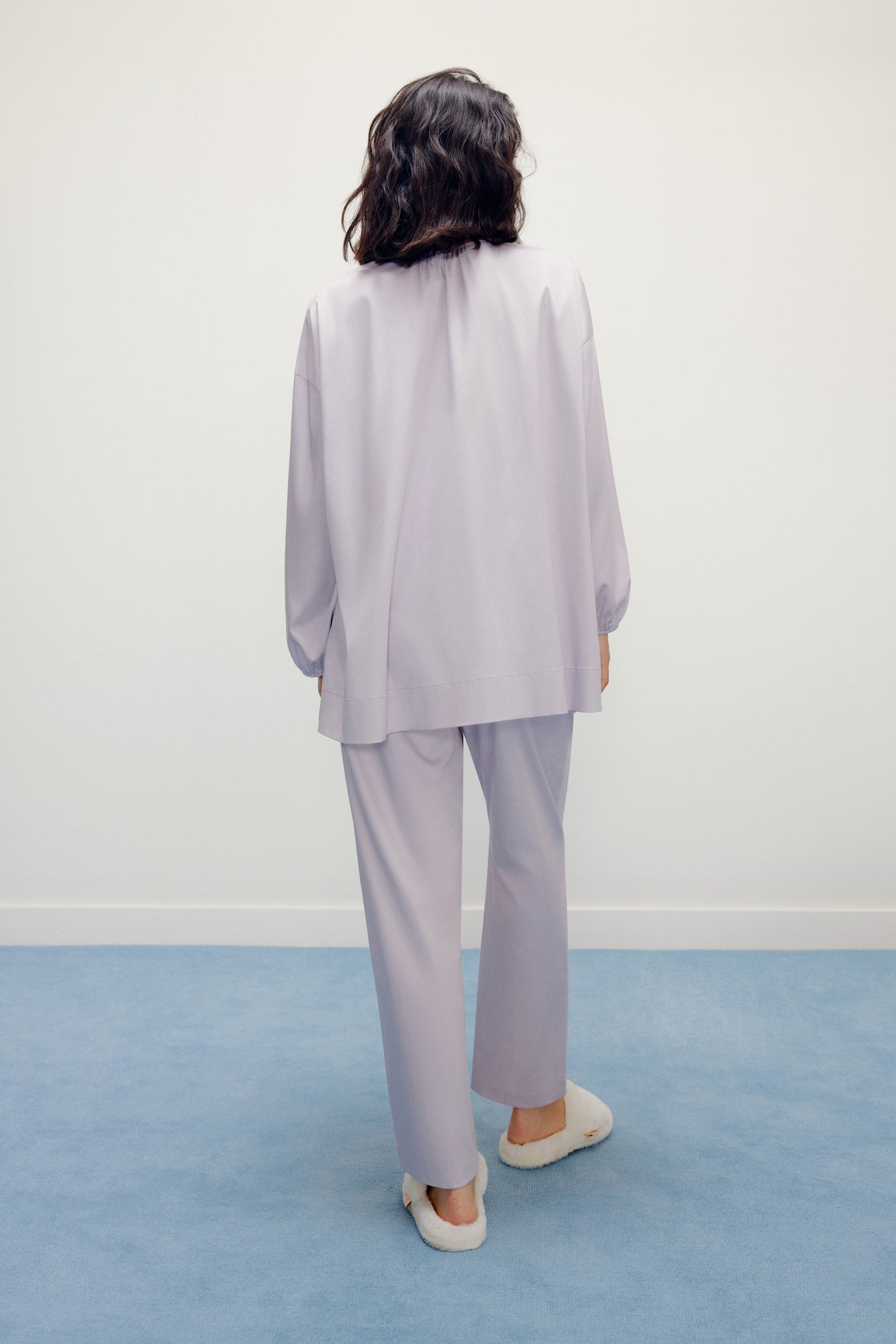 back of a woman wearing a purple pajama sets and white slippers