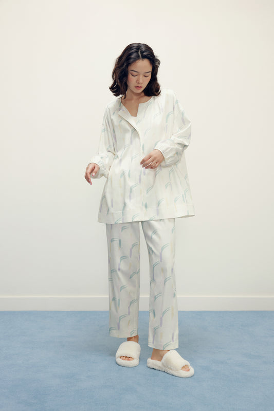 a woman wearing a white pajama sets with pattern and white slippers