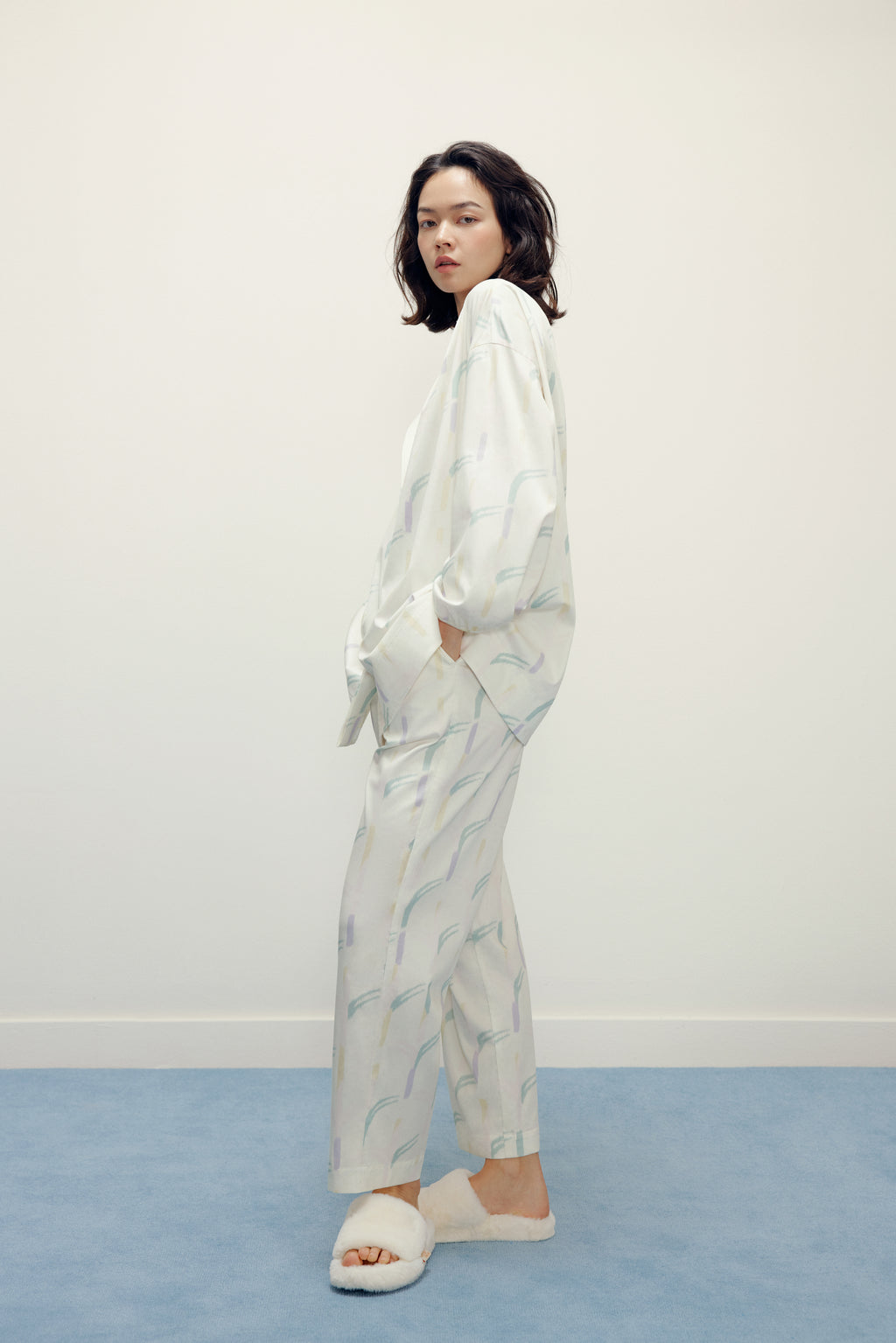 side view of a woman wearing a white pajama sets with pattern and white slippers