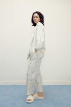 side view of a woman wearing a white pajama sets with pattern and white slippers