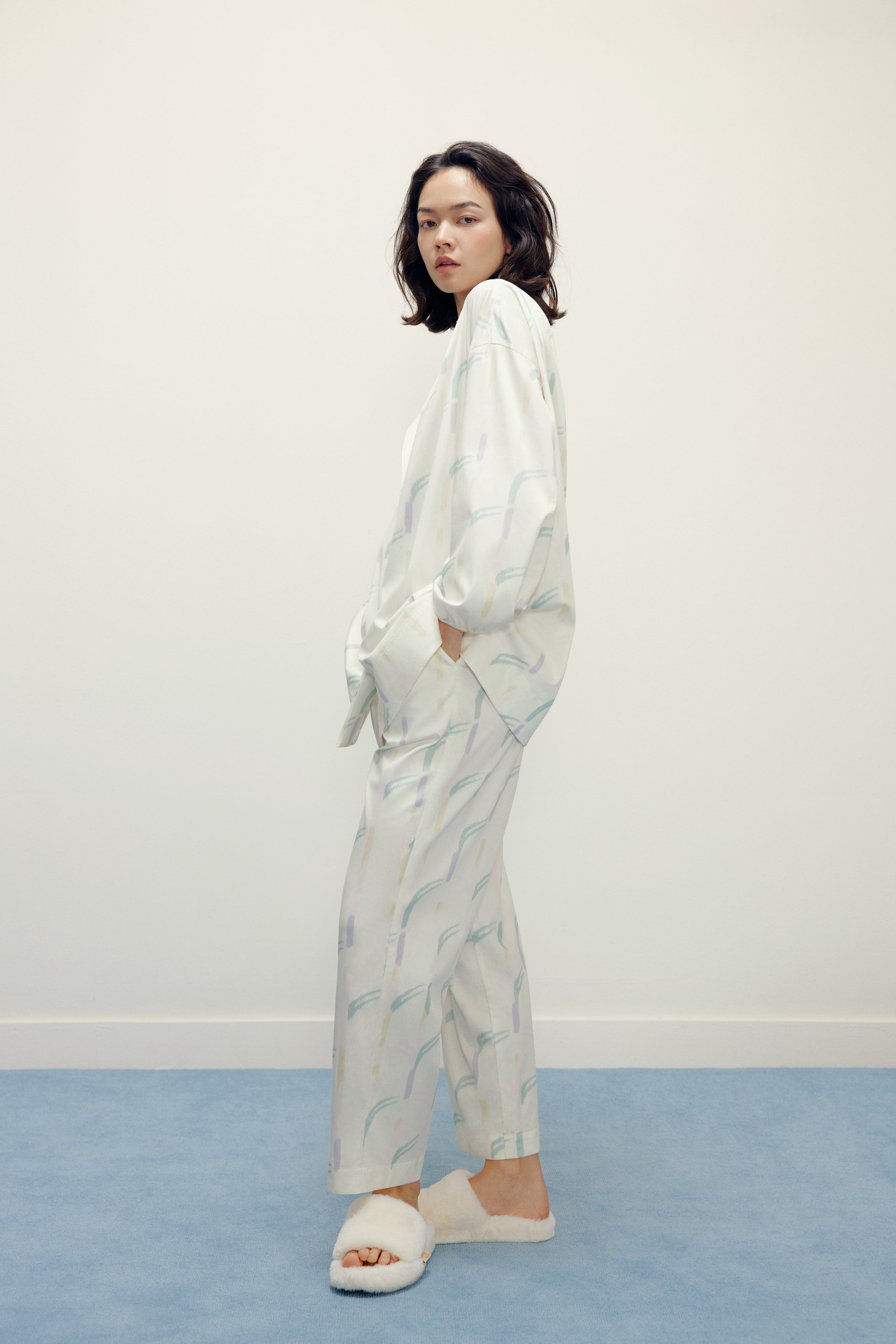 side view of a woman wearing a white pajama sets with pattern and white slippers
