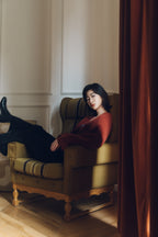 woman sitting on a sofa wearing red wrap cardigan and black pants