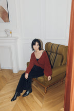 woman sitting on the sofa wearing a red wrap Cardigan and black pants