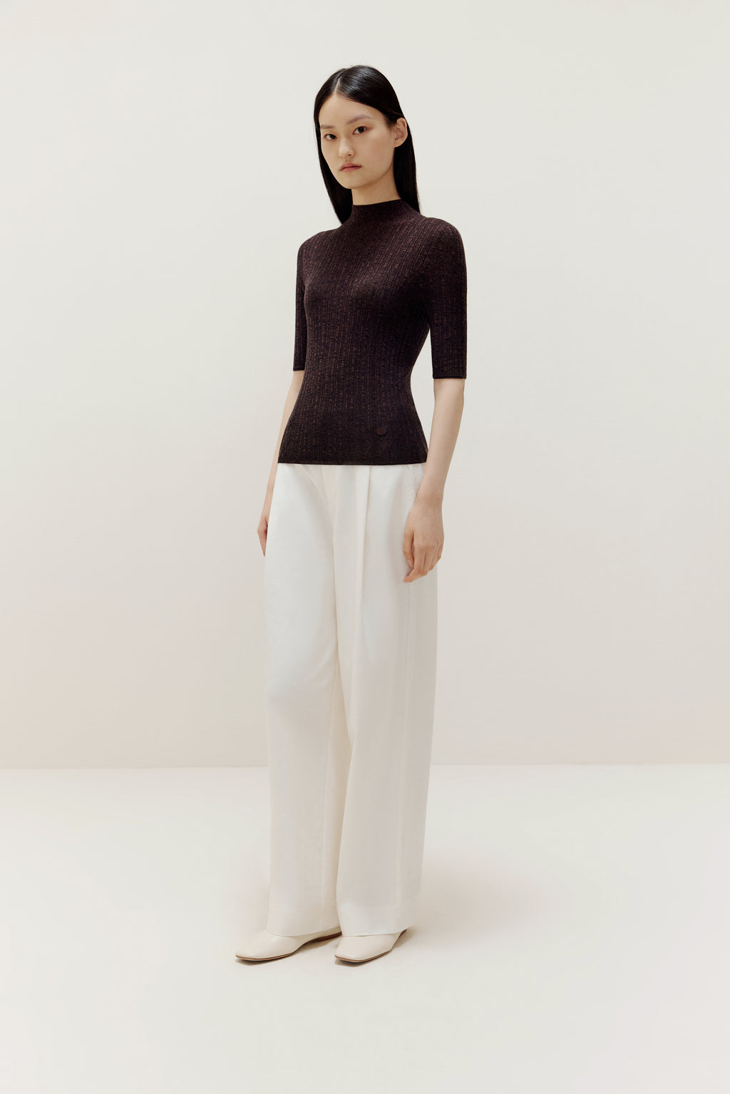 a woman wearing a brown sweater and white pants