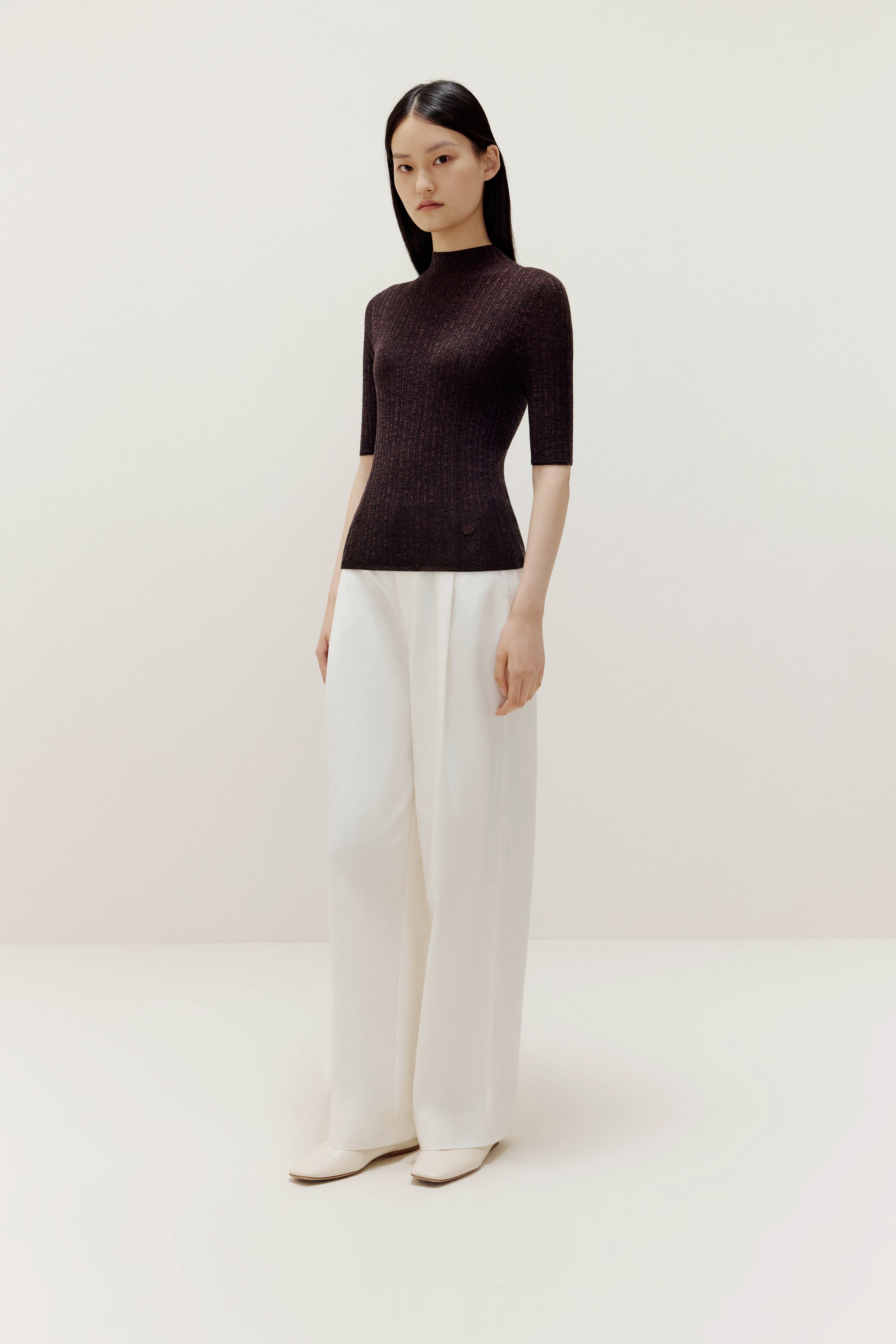 a woman wearing a brown sweater and white pants