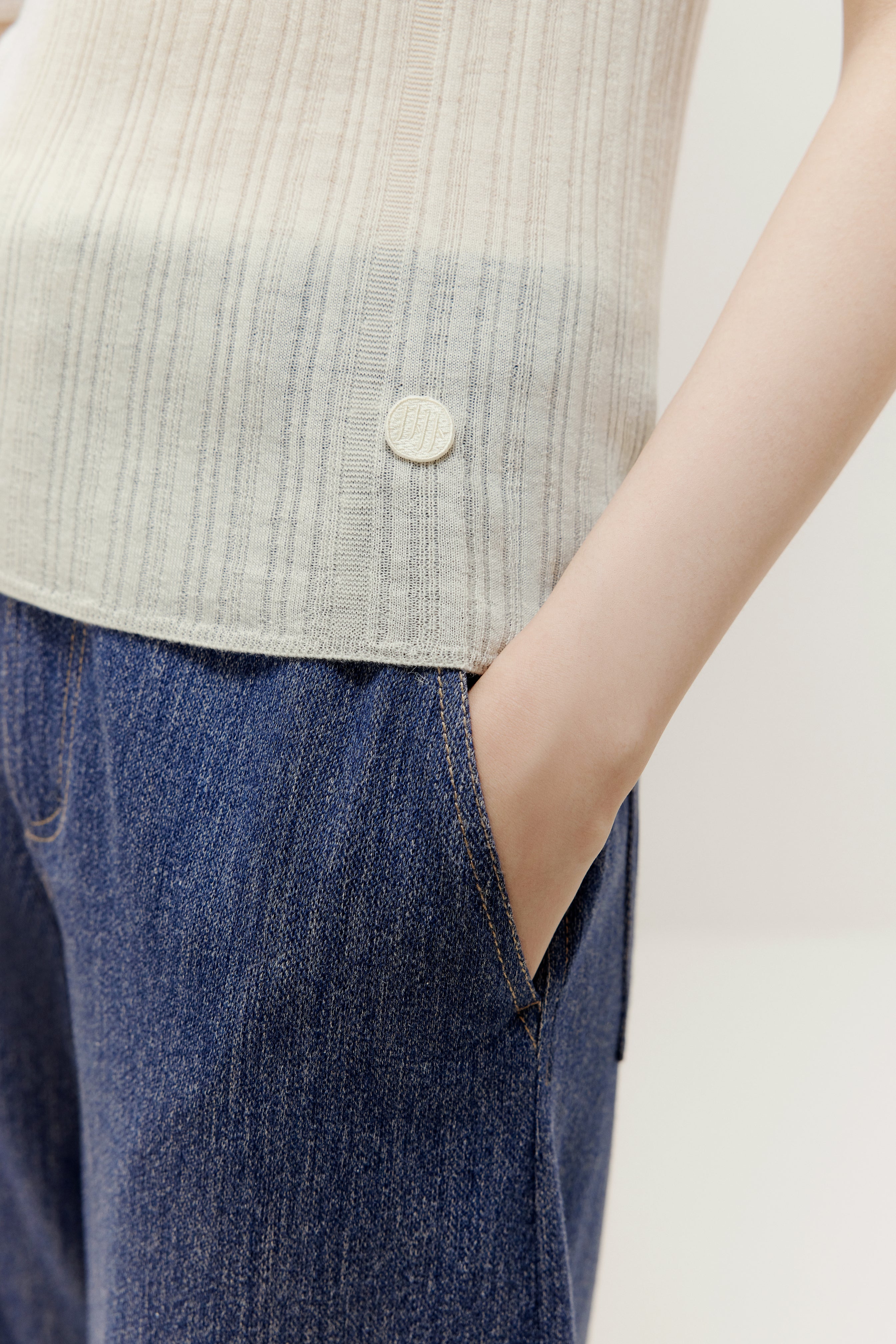 a woman wearing a white sweater with logo and denim 