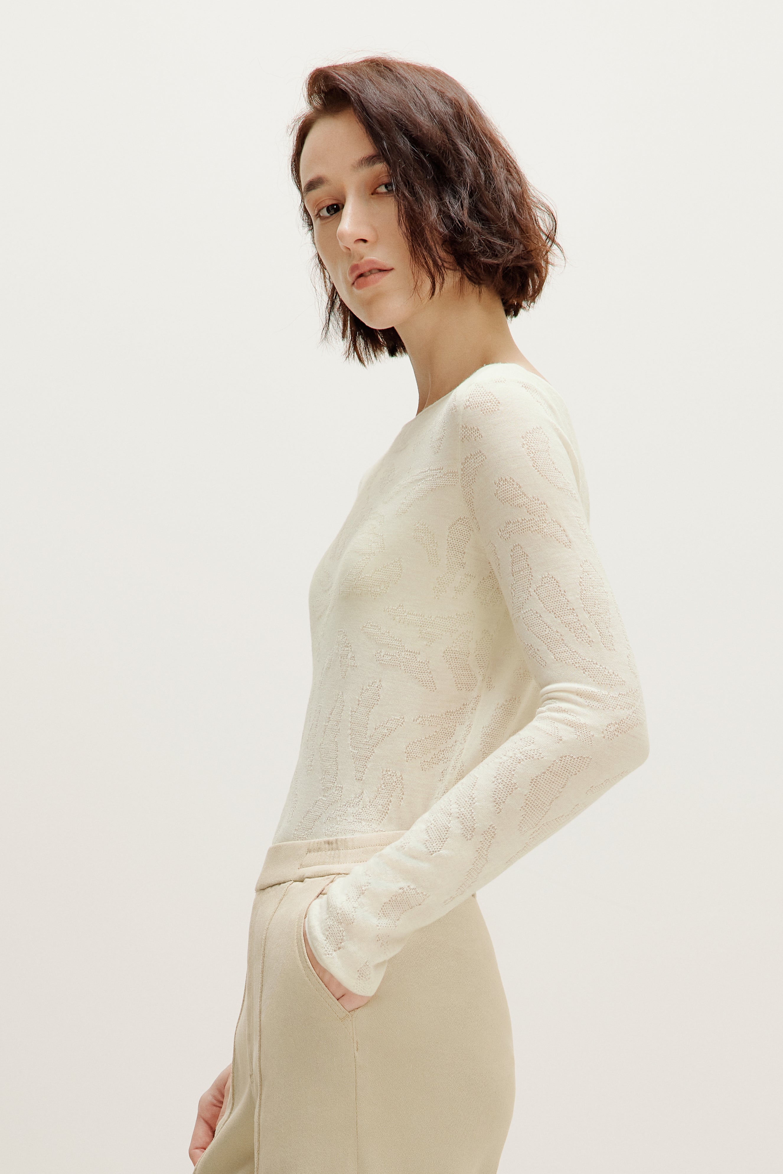 side view of a woman wearing a white sweater and white pants