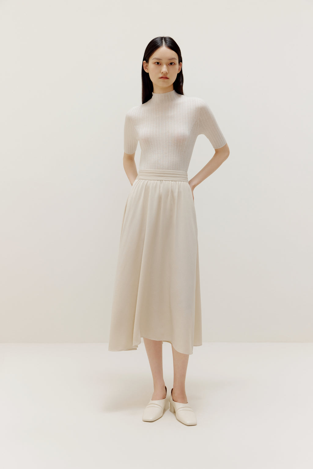 a woman wearing a white sweater and white dress