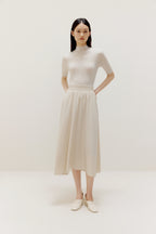 a woman wearing a white sweater and white dress