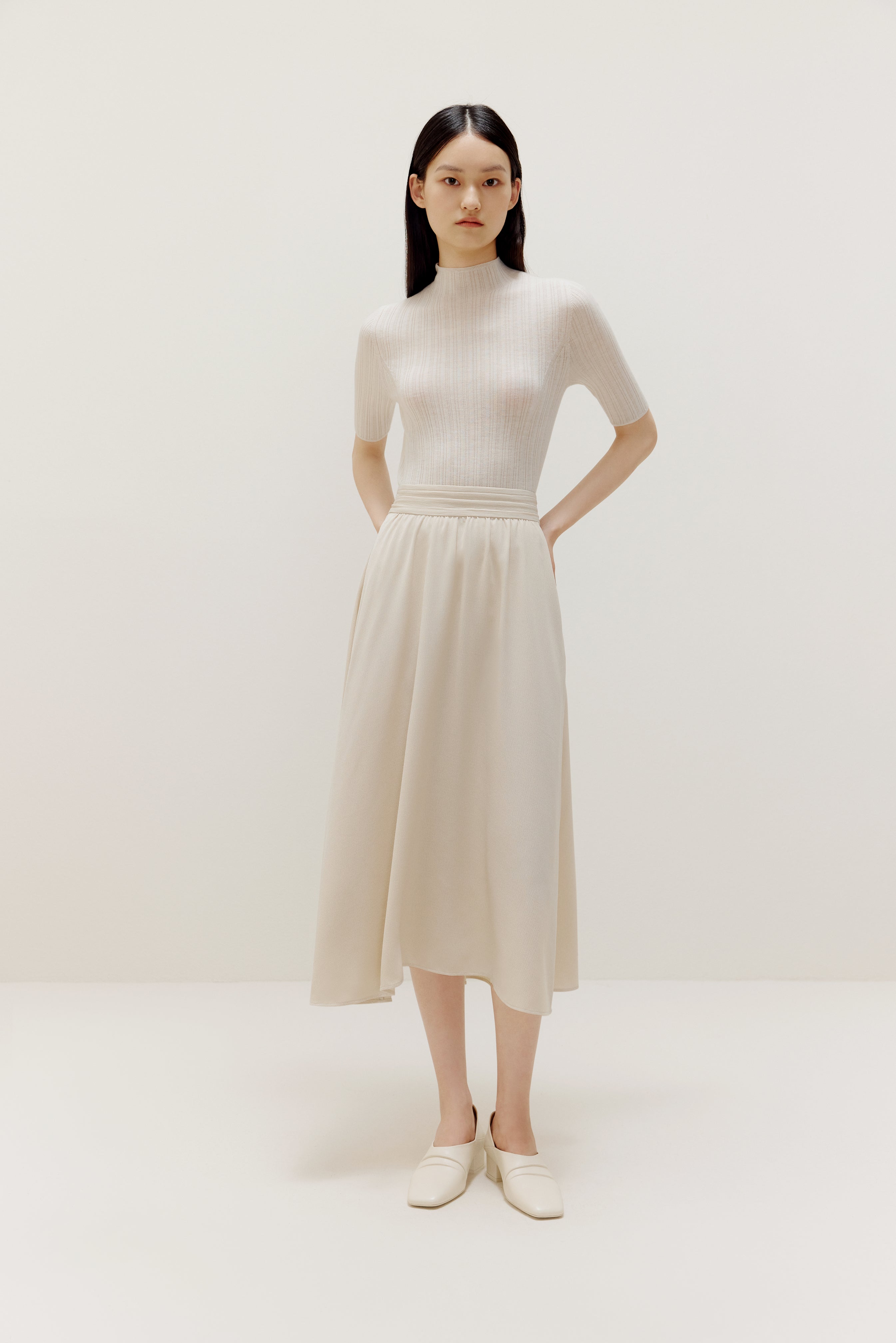 a woman wearing a white sweater and white dress