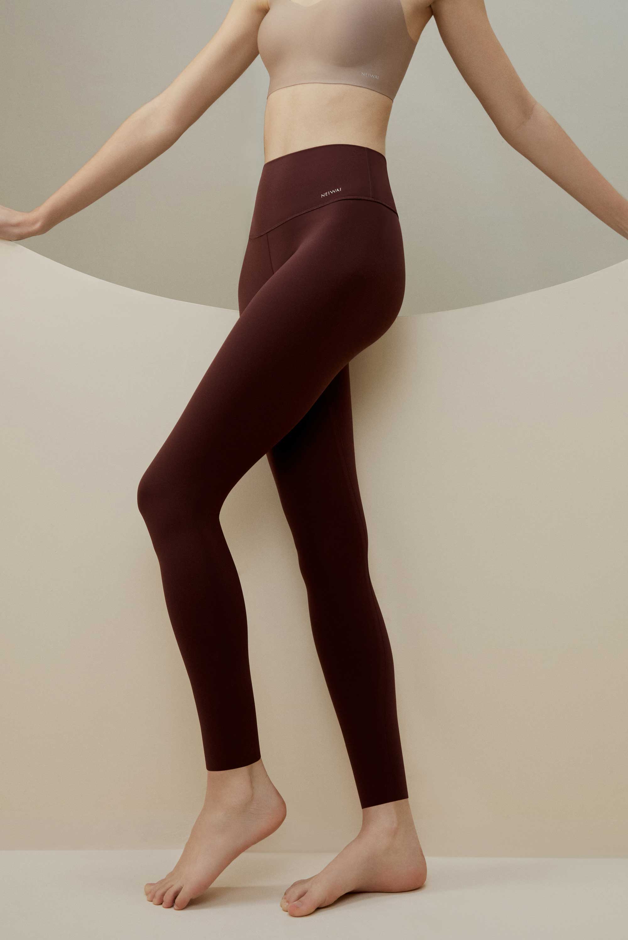 Woman wearing dark maroon leggings and beige bra