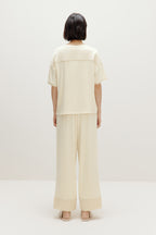 back of woman in cream pajama t-shirt and matching pants