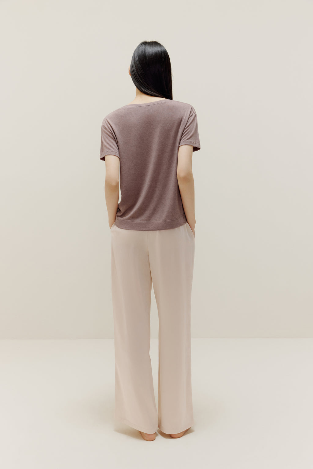 A woman wears a brown short-sleeved shirt and white trousers from back.