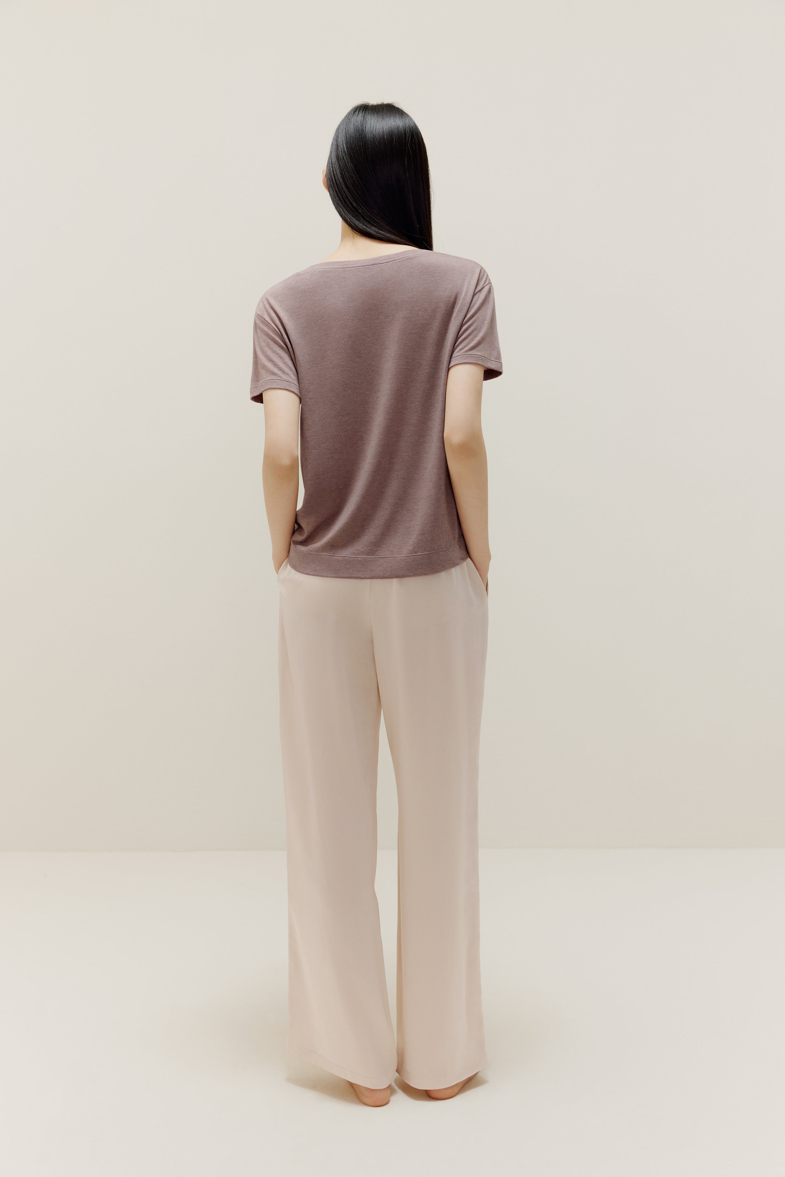 A woman wears a brown short-sleeved shirt and white trousers from back.